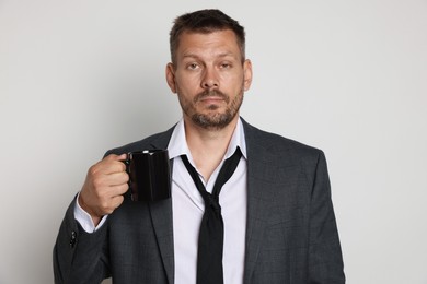 Photo of Man with cup of drink suffering from hangover on white background