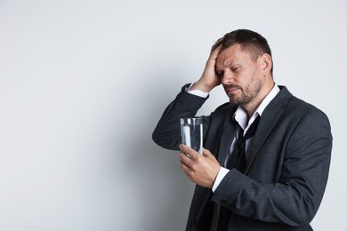 Photo of Man with glass of water suffering from hangover on white background, space for text