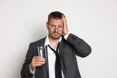 Photo of Man with glass of water suffering from hangover on white background