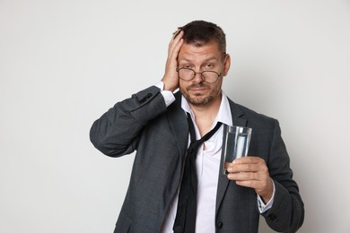 Photo of Man with glass of water suffering from hangover on white background