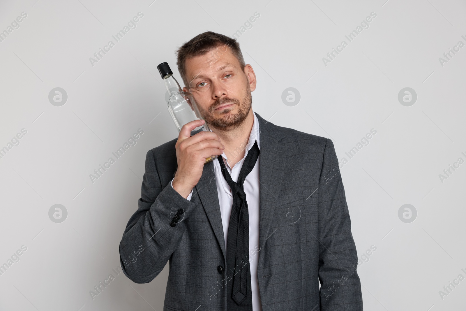 Photo of Man with bottle of whiskey suffering from hangover on white background