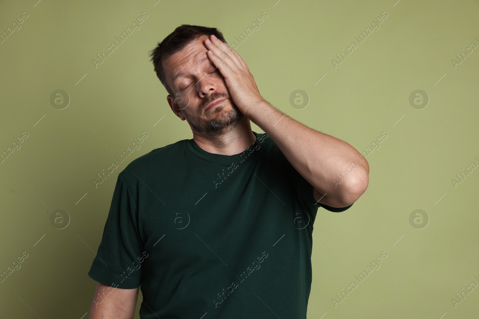Photo of Man suffering from hangover on olive background
