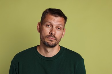 Photo of Man suffering from hangover on olive background
