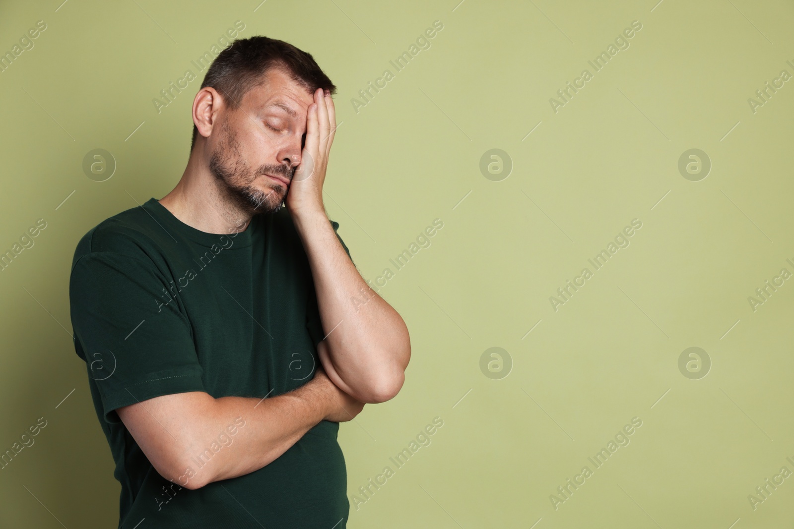 Photo of Man suffering from hangover on olive background, space for text