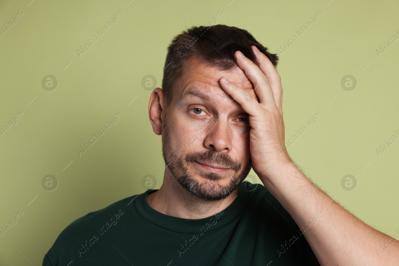 Photo of Man suffering from hangover on olive background