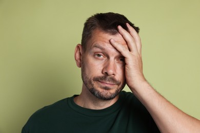 Photo of Man suffering from hangover on olive background