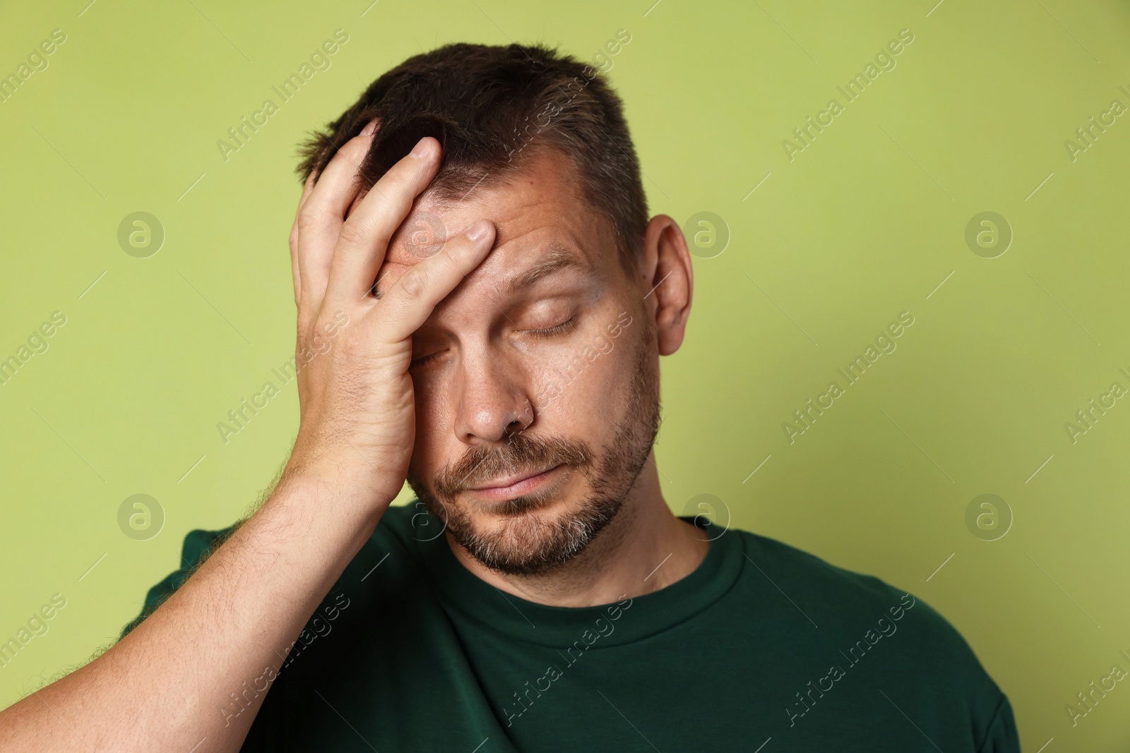 Photo of Man suffering from hangover on olive background