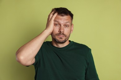 Photo of Man suffering from hangover on olive background