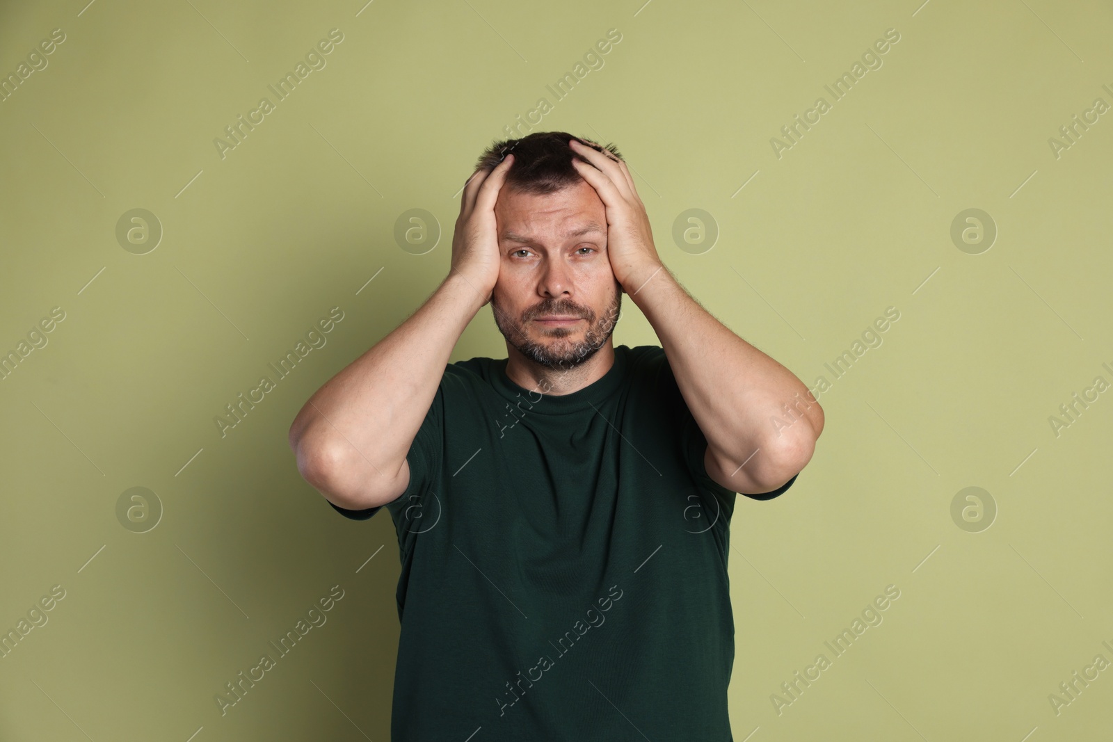 Photo of Man suffering from hangover on olive background
