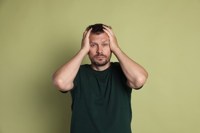 Photo of Man suffering from hangover on olive background