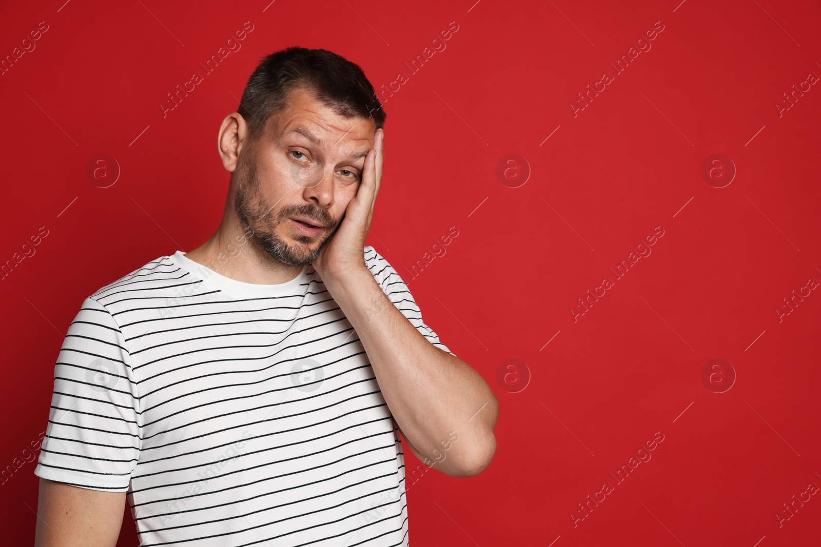 Man suffering from hangover on red background, space for text Photo of Man suffering from hangover on red background, space for text