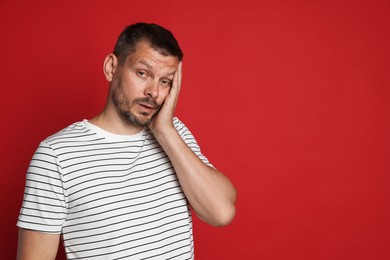 Photo of Man suffering from hangover on red background, space for text