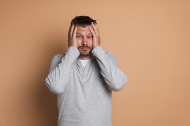 Photo of Man suffering from hangover on beige background