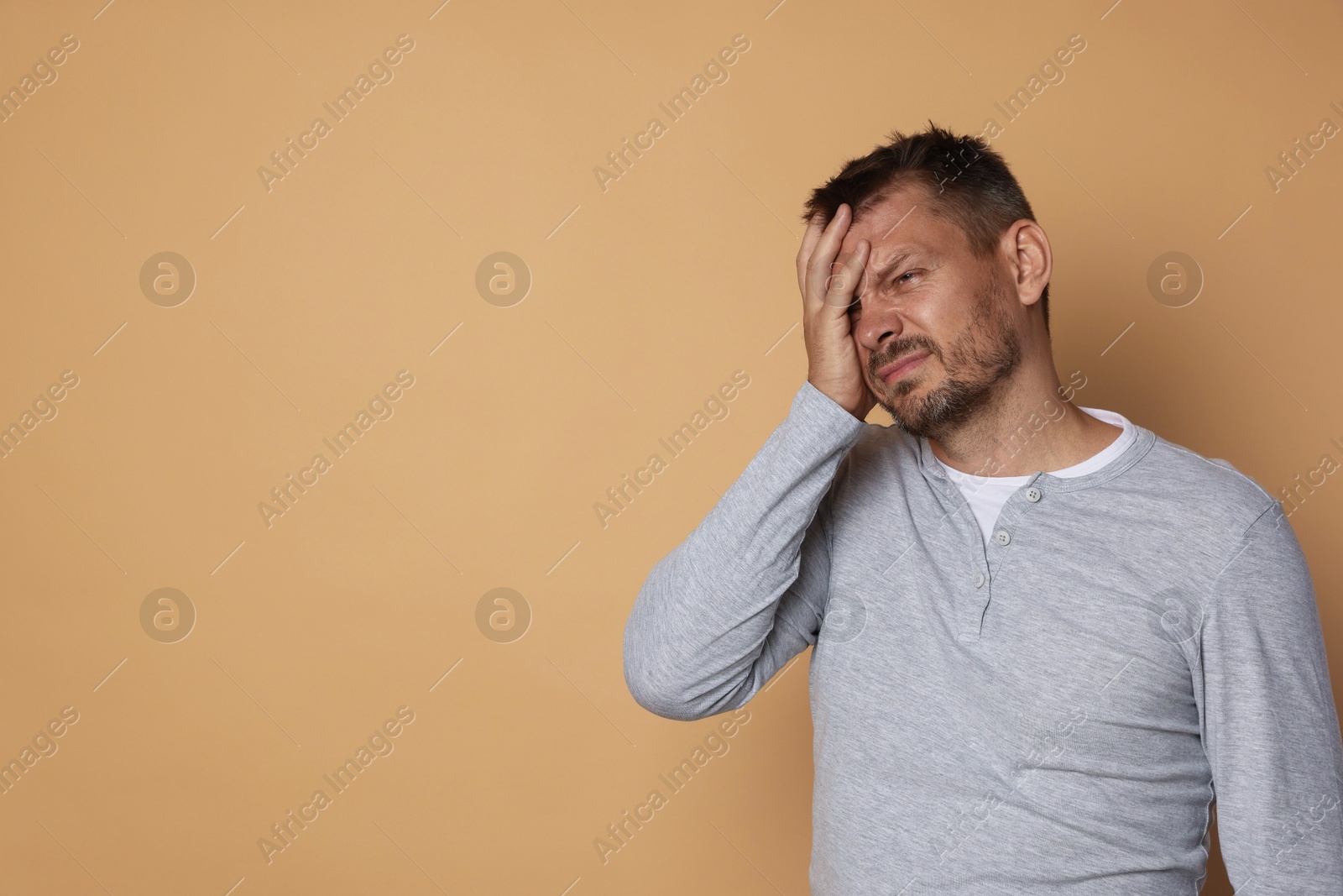 Photo of Man suffering from hangover on beige background, space for text