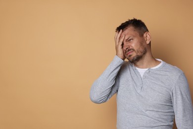 Photo of Man suffering from hangover on beige background, space for text
