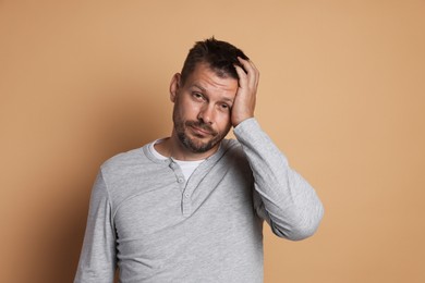 Photo of Man suffering from hangover on beige background
