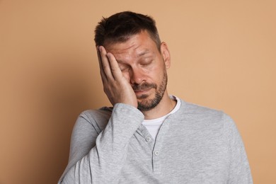 Photo of Man suffering from hangover on beige background