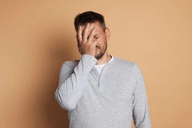 Photo of Man suffering from hangover on beige background
