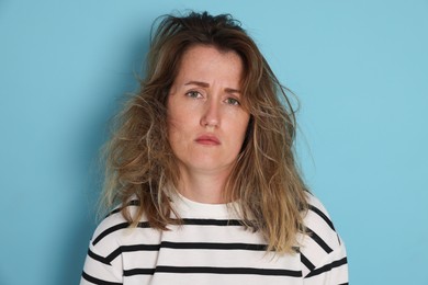 Photo of Woman suffering from hangover on light blue background
