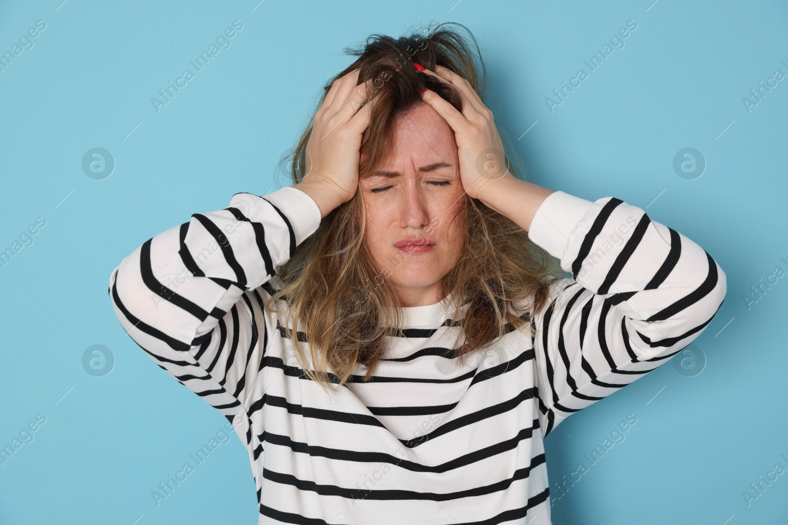 Woman suffering from hangover on light blue background Photo of Woman suffering from hangover on light blue background