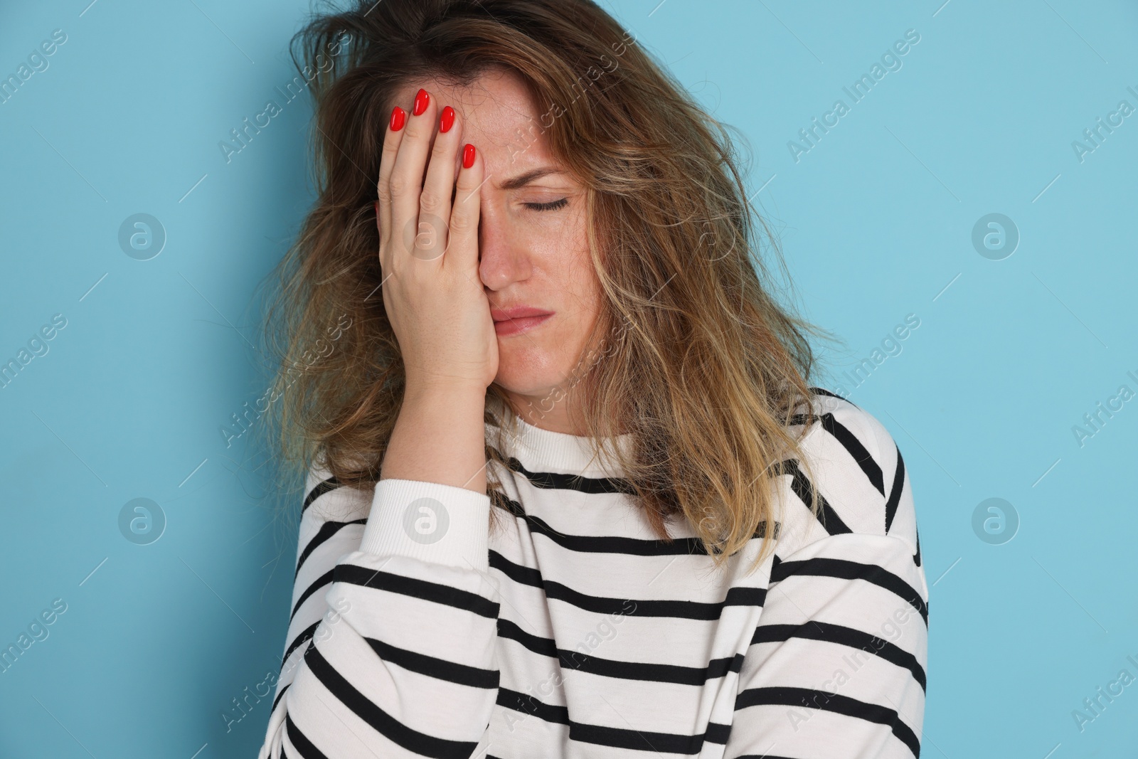Woman suffering from hangover on light blue background Photo of Woman suffering from hangover on light blue background