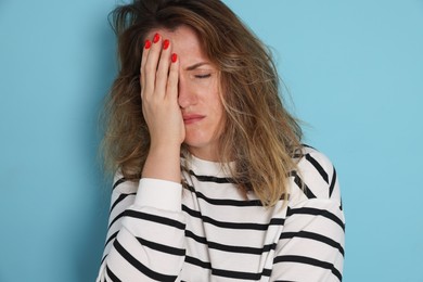 Photo of Woman suffering from hangover on light blue background