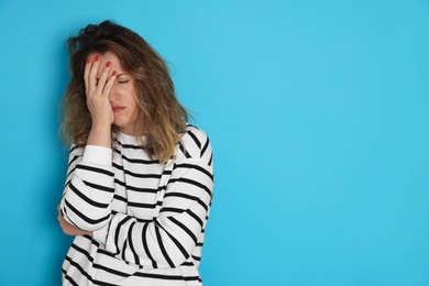Photo of Woman suffering from hangover on light blue background. Space for text