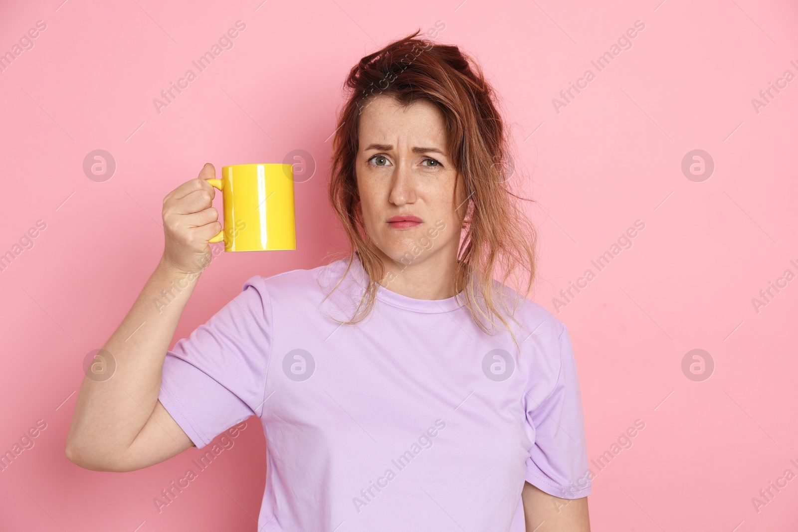 Woman with cup of coffee suffering from hangover on pink background Photo of Woman with cup of coffee suffering from hangover on pink background