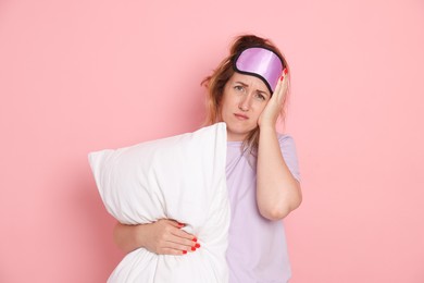 Photo of Woman with pillow suffering from hangover on pink background
