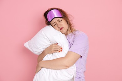 Photo of Woman with pillow suffering from hangover on pink background