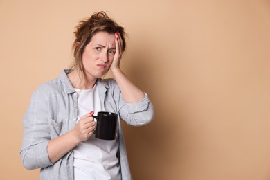 Photo of Woman with cup of coffee suffering from hangover on beige background. Space for text