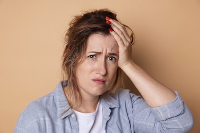 Photo of Woman suffering from hangover on beige background