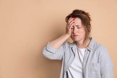 Photo of Woman suffering from hangover on beige background. Space for text