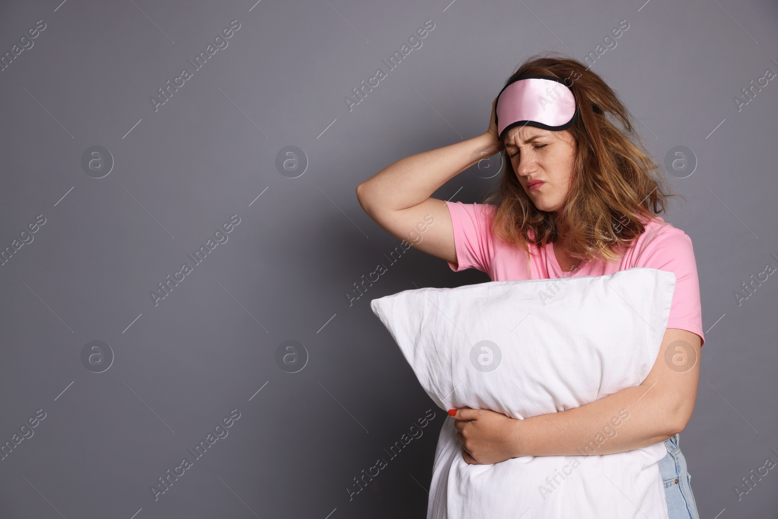 Photo of Woman with pillow suffering from hangover on grey background. Space for text