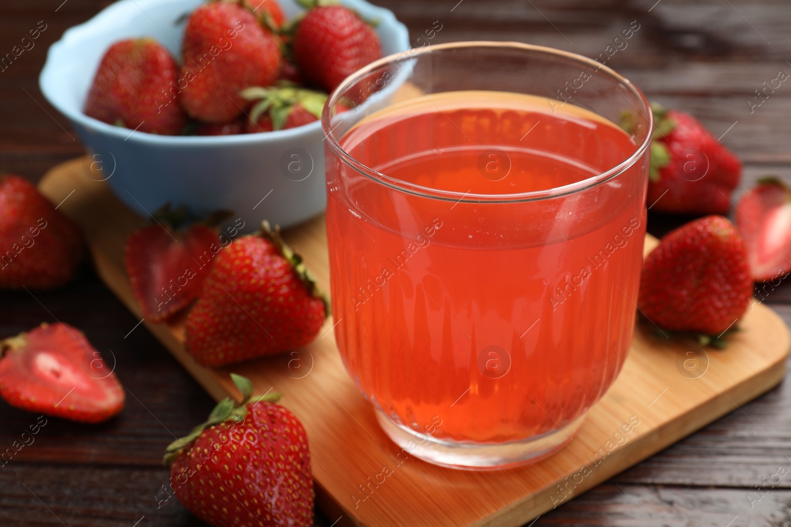 Photo of Tasty compot and strawberries on wooden table, closeup