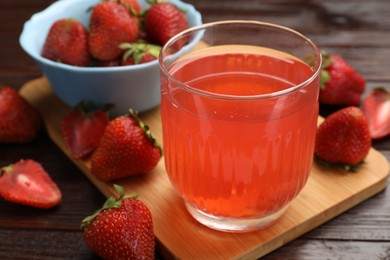Photo of Tasty compot and strawberries on wooden table, closeup