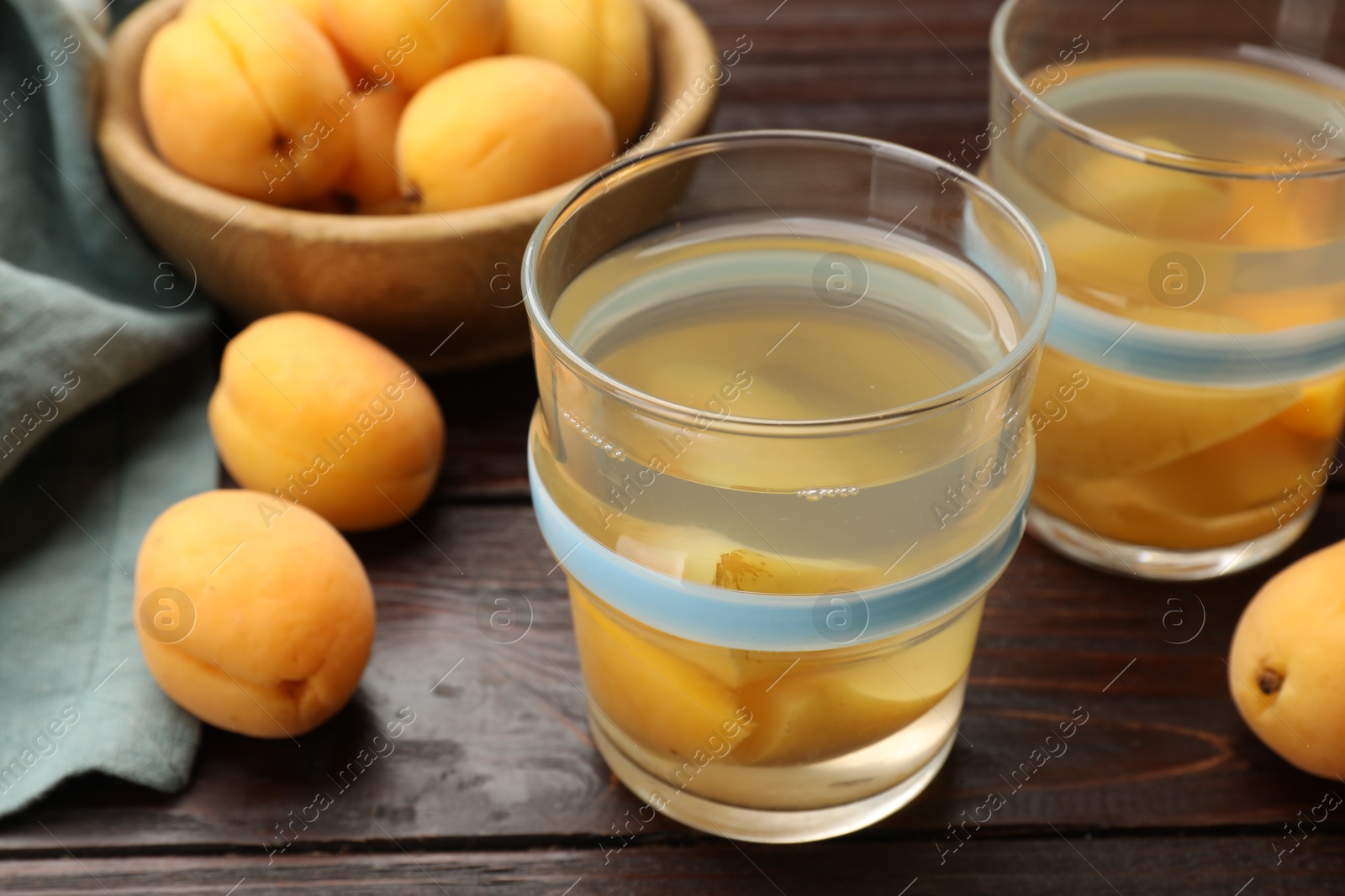 Photo of Tasty compot with apricots on wooden table, closeup