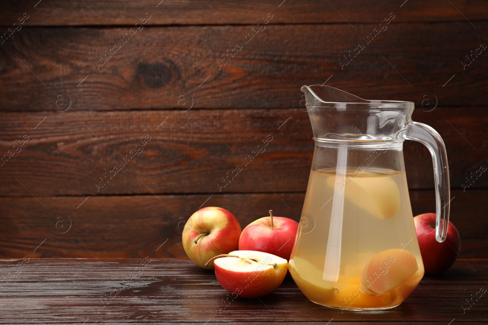 Photo of Tasty compot with apples on wooden table. Space for text