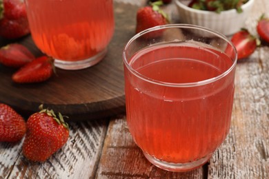 Photo of Tasty compot and strawberries on wooden table, closeup