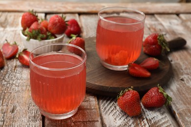 Photo of Tasty compot and strawberries on wooden table, closeup