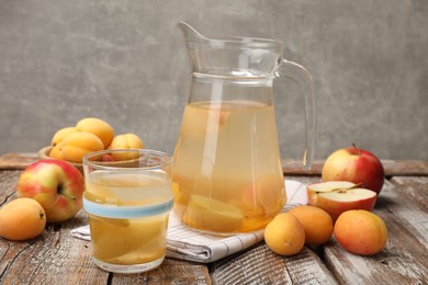 Photo of Tasty compot and fruits on wooden table