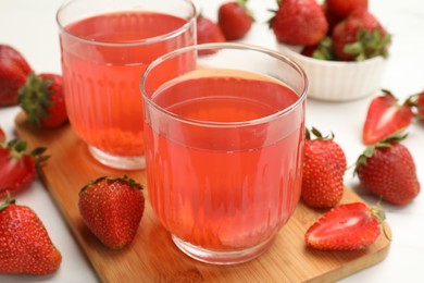 Photo of Tasty compot and strawberries on white table, closeup