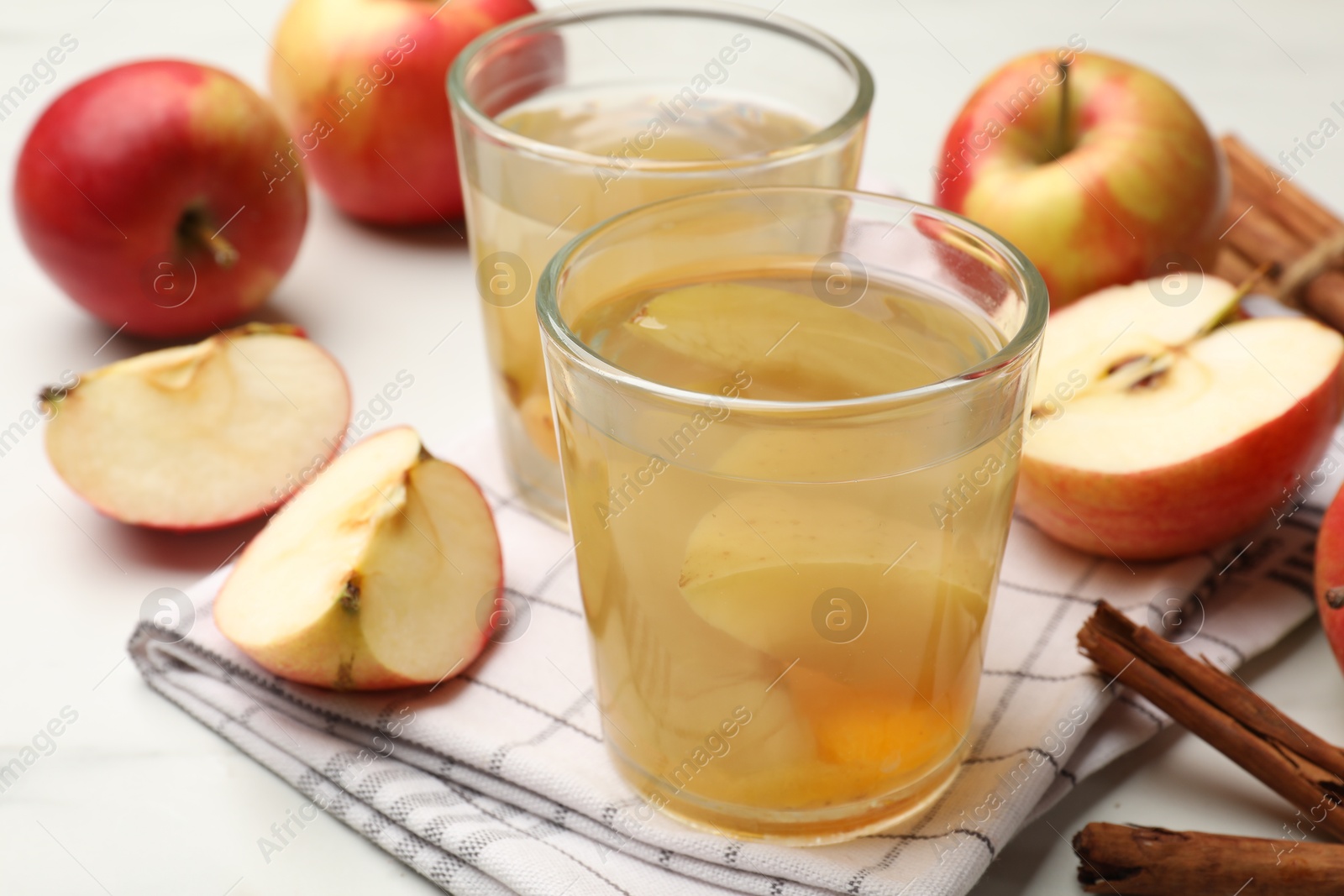 Photo of Tasty compot with apples and cinnamon on white table, closeup