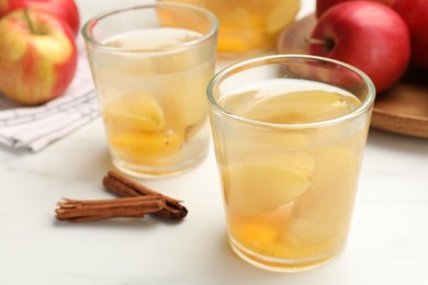 Photo of Tasty compot with apples and cinnamon on white table, closeup