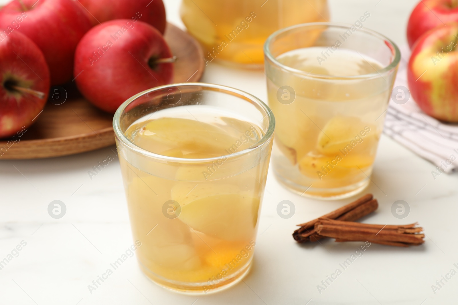 Photo of Tasty compot with apples and cinnamon on white table, closeup