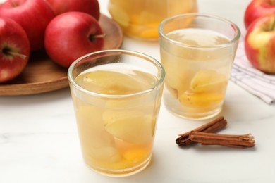 Photo of Tasty compot with apples and cinnamon on white table, closeup