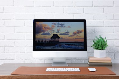 Photo of Stylish workplace with computer and orange mousepad on wooden table indoors