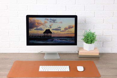 Photo of Stylish workplace with computer and orange mousepad on wooden table indoors