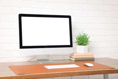 Photo of Stylish workplace with computer and orange mousepad on wooden table indoors. Space for text