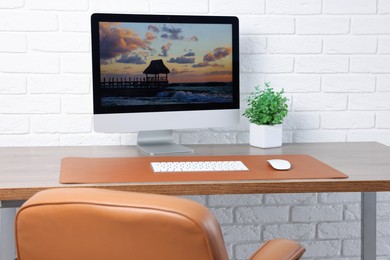 Photo of Stylish workplace with computer and orange mousepad on wooden table indoors